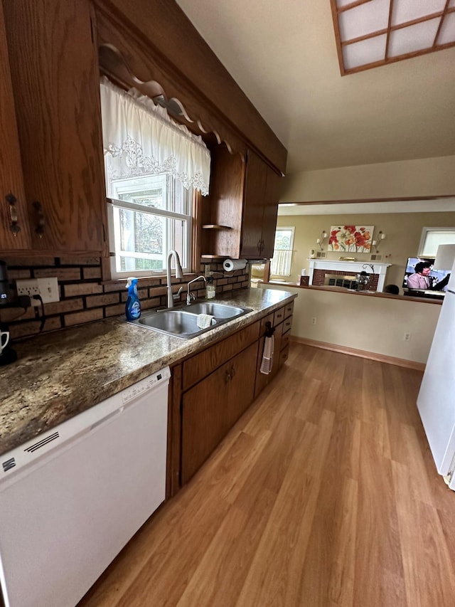 kitchen with sink, decorative backsplash, white dishwasher, and light hardwood / wood-style flooring