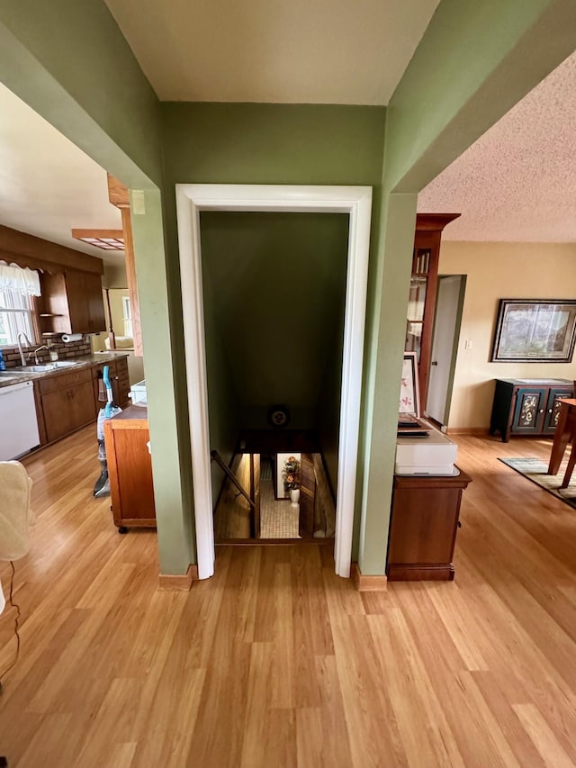 hall featuring sink, light hardwood / wood-style floors, and a textured ceiling