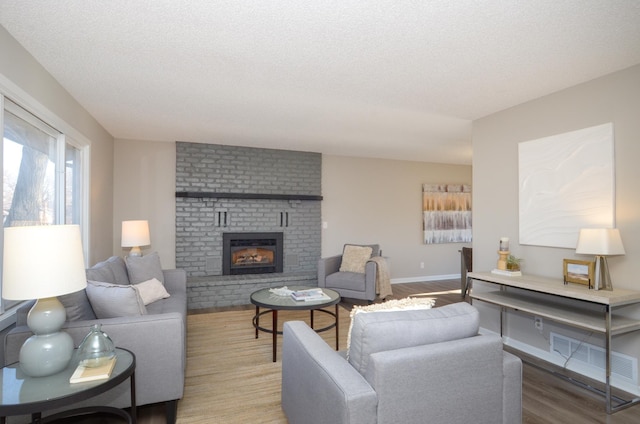 living room featuring hardwood / wood-style flooring, a textured ceiling, and a fireplace