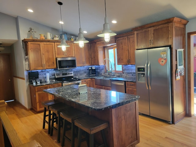 kitchen featuring lofted ceiling, sink, hanging light fixtures, a kitchen island, and stainless steel appliances