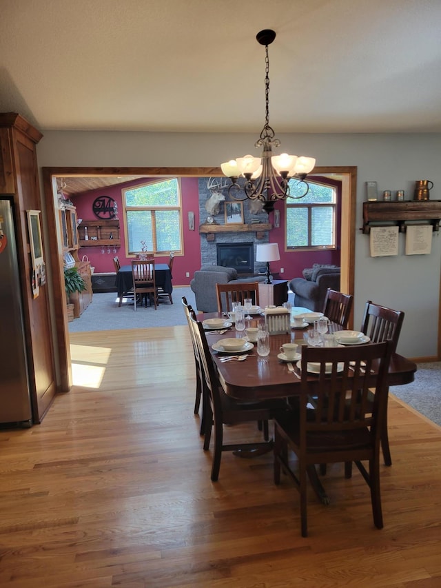 dining area featuring a fireplace, a chandelier, light hardwood / wood-style flooring, and a wealth of natural light