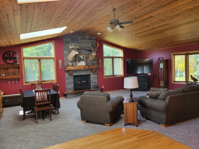 living room featuring wood ceiling, a fireplace, vaulted ceiling with skylight, and a wealth of natural light