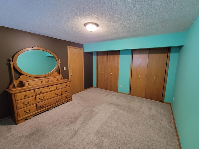 carpeted bedroom with a textured ceiling and multiple closets