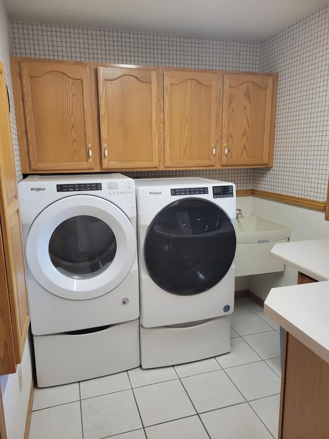 laundry area with cabinets, separate washer and dryer, and light tile patterned floors