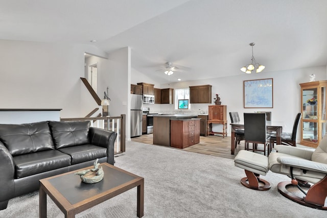 living room featuring lofted ceiling, ceiling fan with notable chandelier, and light colored carpet