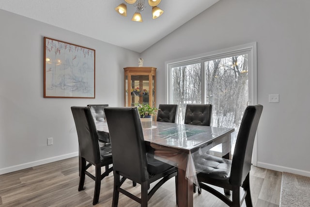 dining room with an inviting chandelier, lofted ceiling, and hardwood / wood-style flooring