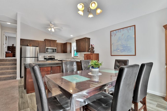 dining space featuring lofted ceiling, sink, ceiling fan with notable chandelier, and light hardwood / wood-style floors