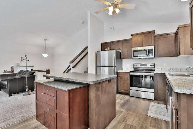 kitchen featuring appliances with stainless steel finishes, decorative light fixtures, a center island, and sink