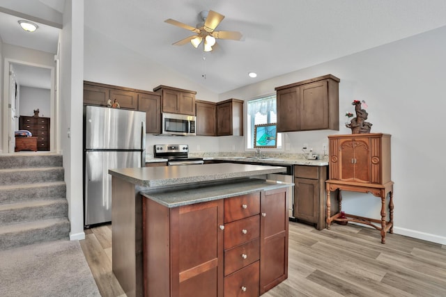 kitchen with lofted ceiling, light hardwood / wood-style flooring, ceiling fan, appliances with stainless steel finishes, and a kitchen island