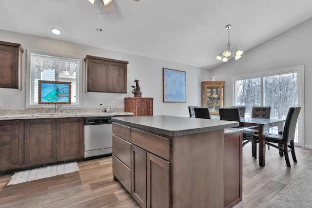 kitchen with pendant lighting, dishwasher, lofted ceiling, a center island, and dark brown cabinetry