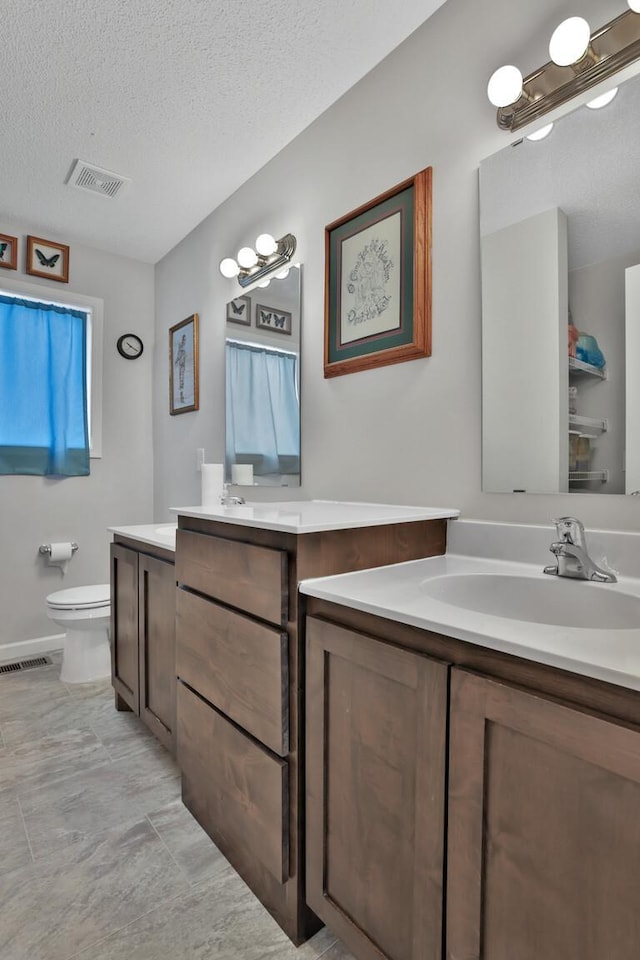 bathroom featuring vanity, a textured ceiling, and toilet