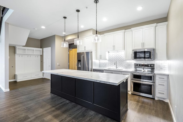 kitchen with stainless steel appliances, a kitchen island, pendant lighting, and white cabinets