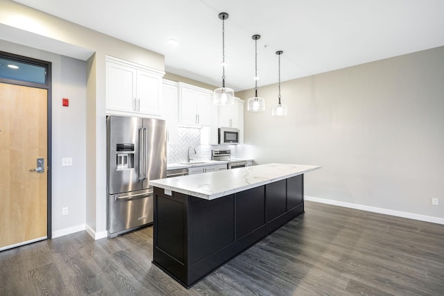 kitchen featuring tasteful backsplash, a center island, stainless steel appliances, light stone countertops, and white cabinets