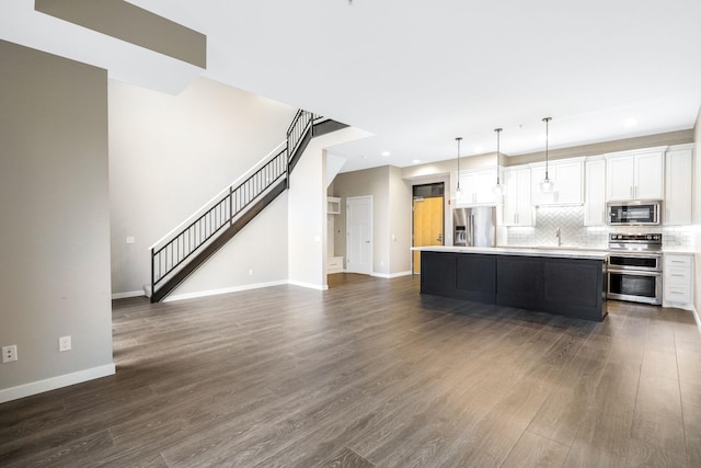 kitchen featuring a kitchen island, decorative light fixtures, tasteful backsplash, white cabinets, and stainless steel appliances