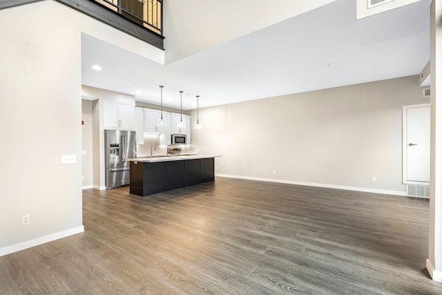 kitchen with appliances with stainless steel finishes, hardwood / wood-style floors, a center island, white cabinets, and decorative light fixtures