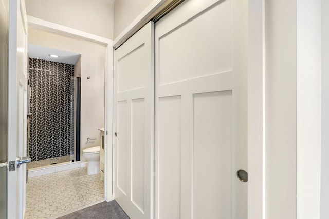 bathroom featuring a tile shower, tile patterned floors, and toilet