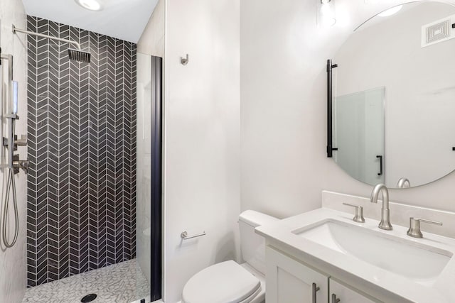 bathroom featuring vanity, toilet, and a tile shower