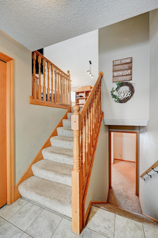 staircase with carpet and a textured ceiling