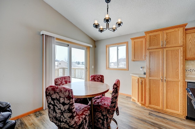 dining room with a notable chandelier, baseboards, light wood-style floors, and lofted ceiling