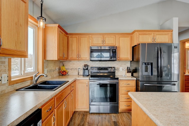 kitchen with sink, tasteful backsplash, decorative light fixtures, vaulted ceiling, and stainless steel appliances