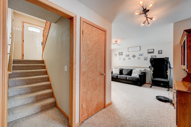 stairs featuring baseboards, carpet, a chandelier, and a textured ceiling