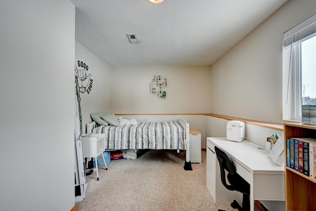 bedroom featuring light colored carpet and a textured ceiling