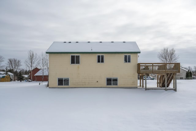 snow covered rear of property with stairway and a deck