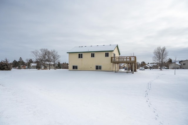 snow covered back of property featuring a deck and stairway