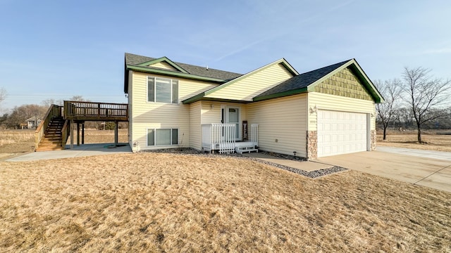 view of front of house featuring stairs, roof with shingles, a deck, a garage, and driveway