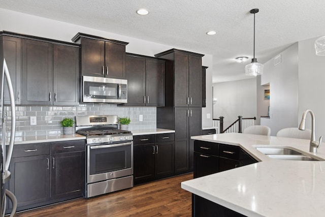 kitchen with visible vents, dark wood-style floors, decorative light fixtures, stainless steel appliances, and a sink