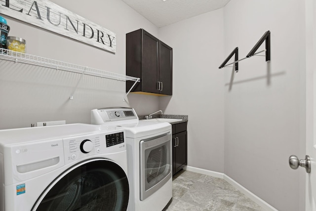 laundry area featuring cabinet space, a sink, a textured ceiling, separate washer and dryer, and baseboards