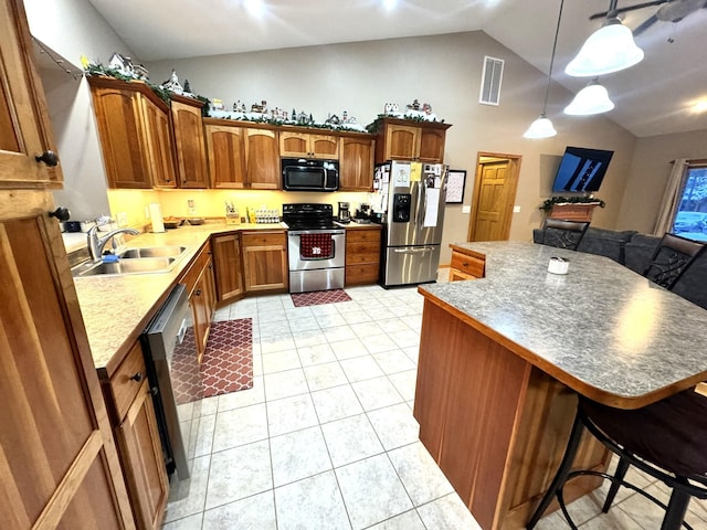 kitchen featuring light tile patterned floors, sink, a breakfast bar, appliances with stainless steel finishes, and hanging light fixtures