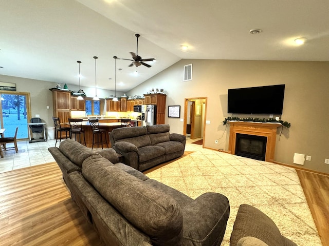 living room with indoor bar, vaulted ceiling, ceiling fan, and light wood-type flooring