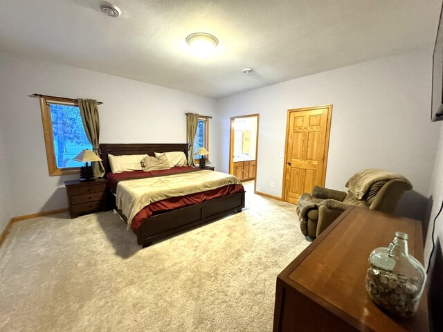 bedroom with light colored carpet and ensuite bath