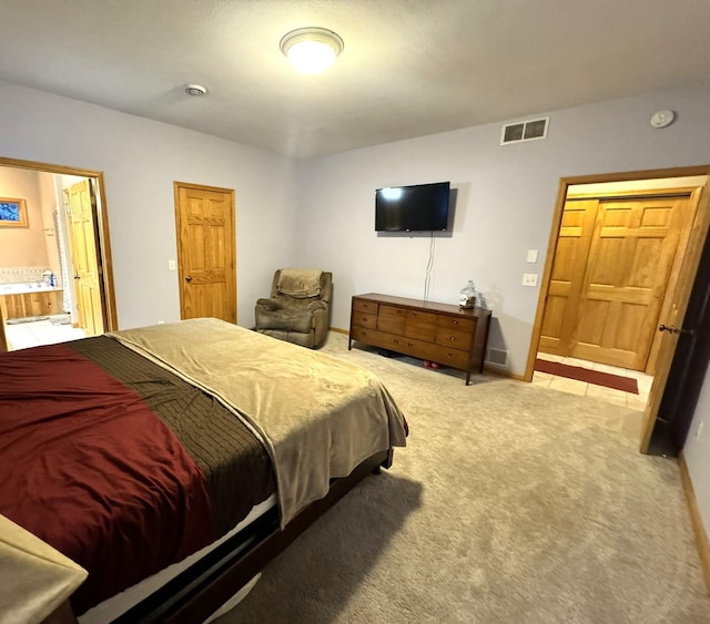 bedroom with connected bathroom and light carpet