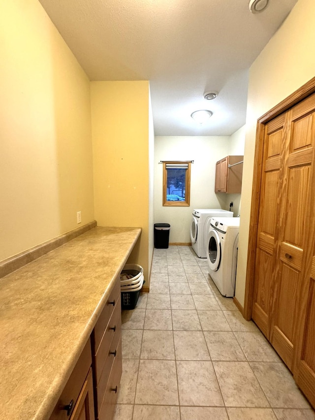 laundry area with washer and clothes dryer, cabinets, and light tile patterned flooring