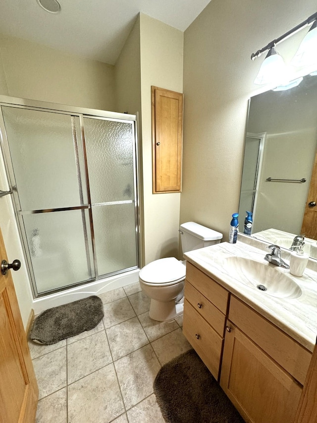 bathroom with a shower with door, vanity, tile patterned flooring, and toilet