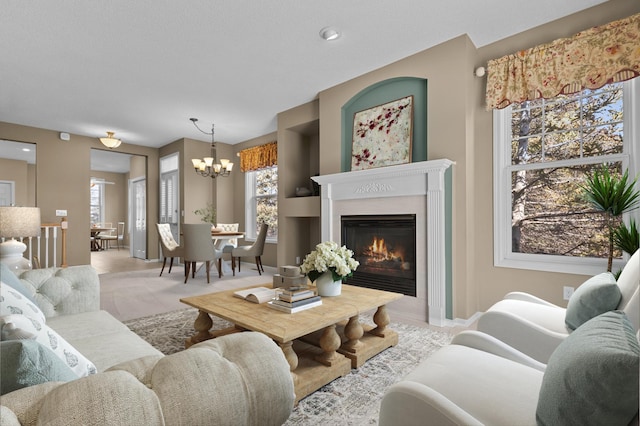 living area featuring baseboards, a notable chandelier, and a glass covered fireplace