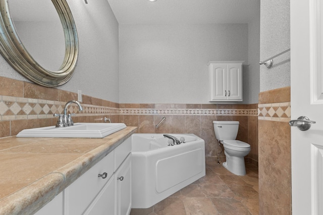 full bath featuring wainscoting, toilet, a bath, vanity, and tile walls