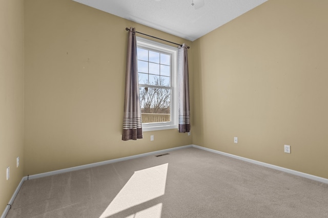 carpeted empty room featuring a textured ceiling, ceiling fan, visible vents, and baseboards