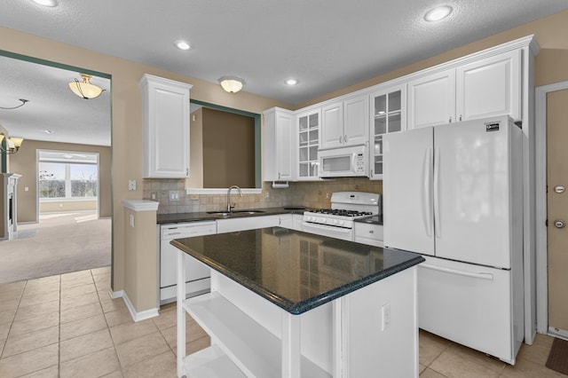 kitchen with tasteful backsplash, glass insert cabinets, white cabinets, a sink, and white appliances