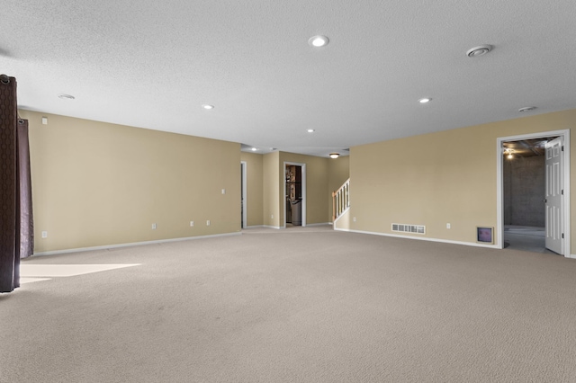 spare room featuring recessed lighting, light colored carpet, visible vents, a textured ceiling, and stairs