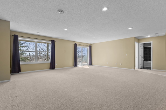 empty room featuring recessed lighting, light colored carpet, a textured ceiling, and baseboards