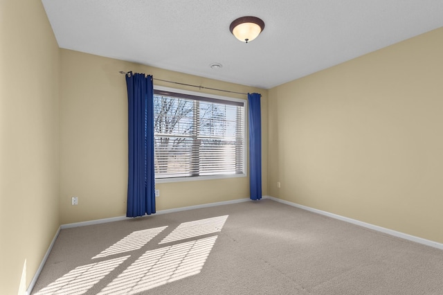 spare room featuring a textured ceiling, carpet, and baseboards