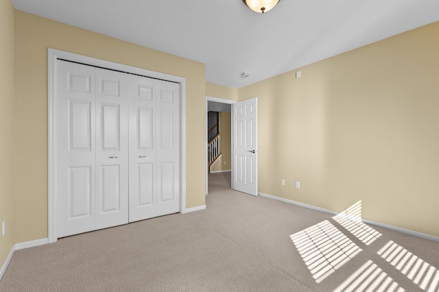 unfurnished bedroom with a closet, carpet, and baseboards