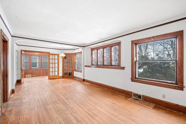 spare room featuring hardwood / wood-style floors, crown molding, a notable chandelier, and a textured ceiling