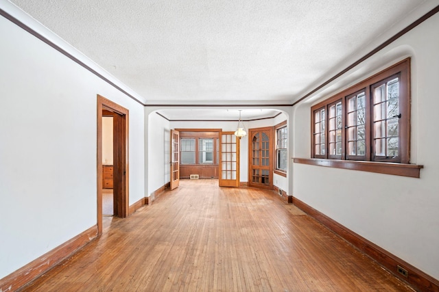 spare room with hardwood / wood-style flooring, ornamental molding, and a textured ceiling