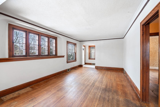 spare room with hardwood / wood-style flooring, ornamental molding, and a textured ceiling