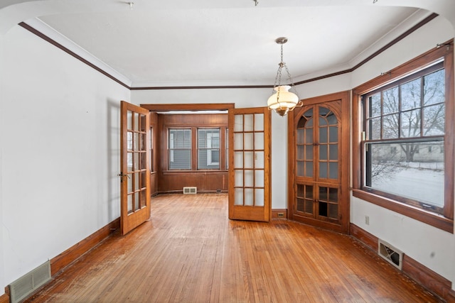 empty room featuring crown molding, light hardwood / wood-style flooring, and french doors