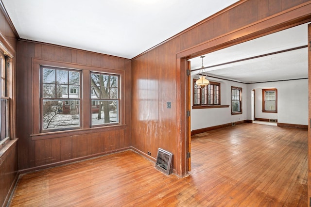 spare room with wooden walls and light wood-type flooring